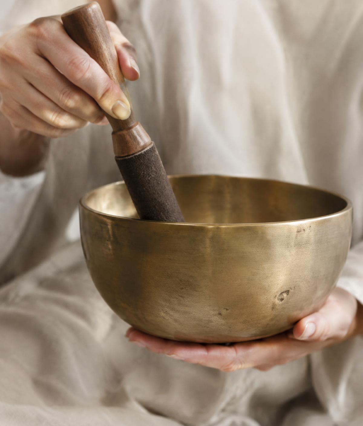 Hands playing a brass singing bowl